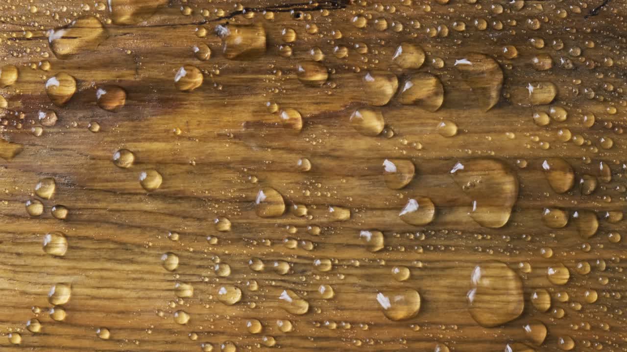 Raindrops on a wooden board. The wind blows off drops of water.