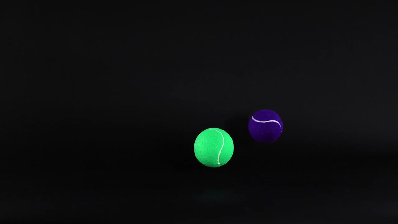 Tennis balls moving against a dark background