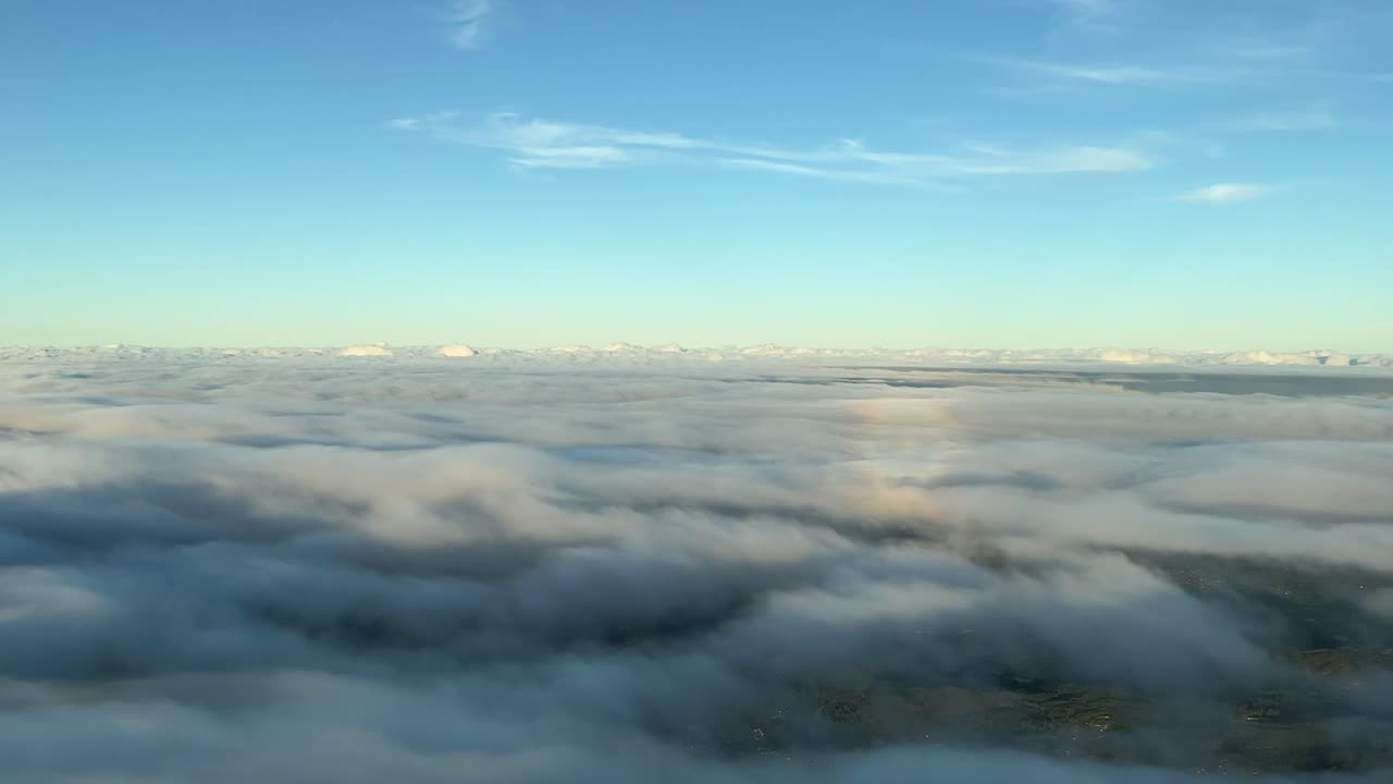vista lateral izquierda del halo de un avión volando sobre una manta de nubes con la luz cálida de la tarde