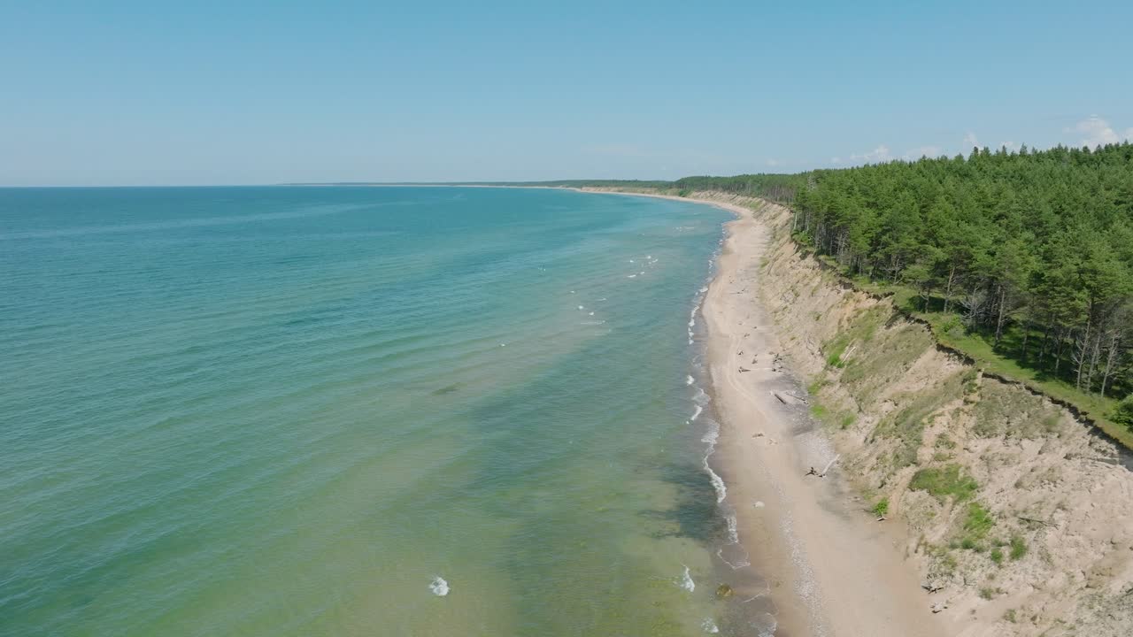 Aerial establishing view of Baltic sea beach at Jurkalne on a sunny summer day, white sand cliff damaged by waves, coastal erosion, climate changes, ascending drone dolly shot moving right