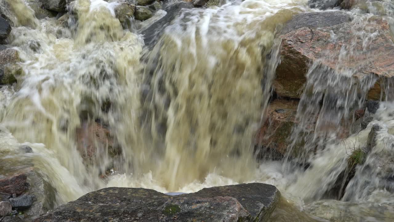 agua de fuertes lluvias e inundaciones que fluye sobre las rocas en el drenaje de la carretera en noruega