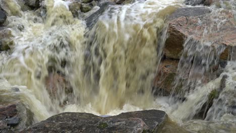 agua de fuertes lluvias e inundaciones que fluye sobre las rocas en el drenaje de la carretera en noruega