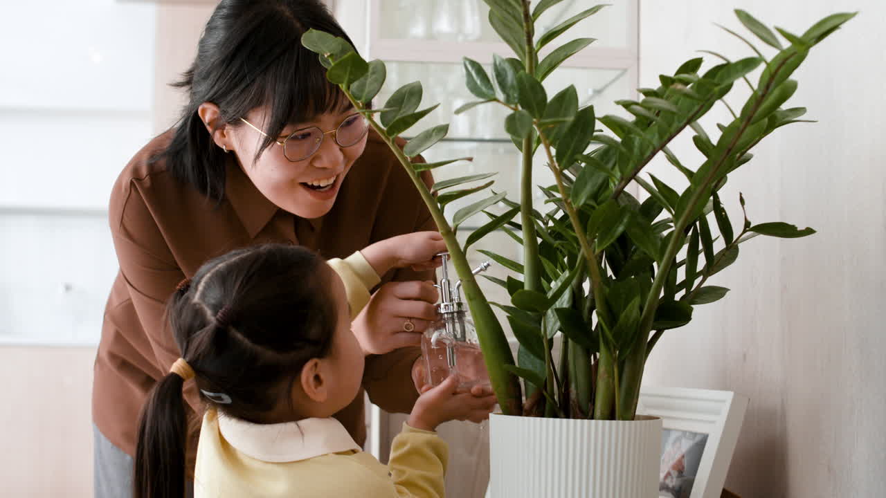 Mother and Daughter Watering a Plant