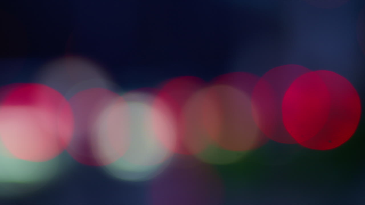 Morbidi cerchi bokeh rossi e bianchi formano una scena notturna astratta e sfocata di città che evoca atmosfera, movimento e ambiente urbano. Ottimo come sfondo o texture per progetti creativi e di design. 4K