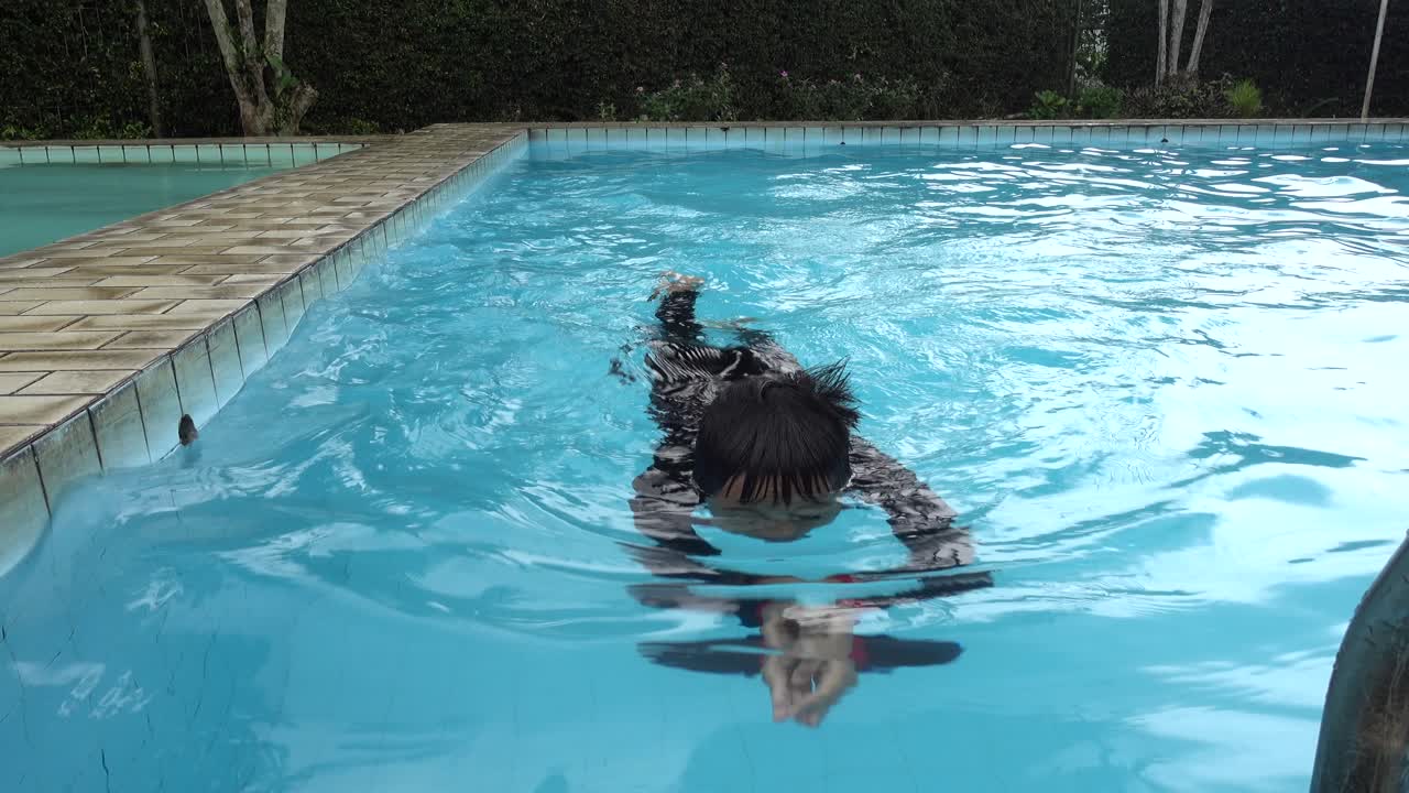 chico asiático nadando en la piscina