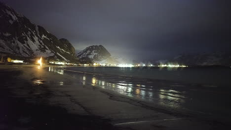 tranquila playa de rambergstranda por la noche con montañas nevadas en ramberg, noruega