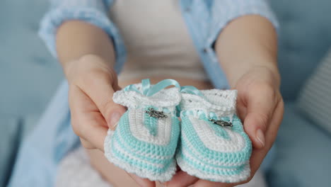 crocheted baby shoes in hands of a pregnant woman