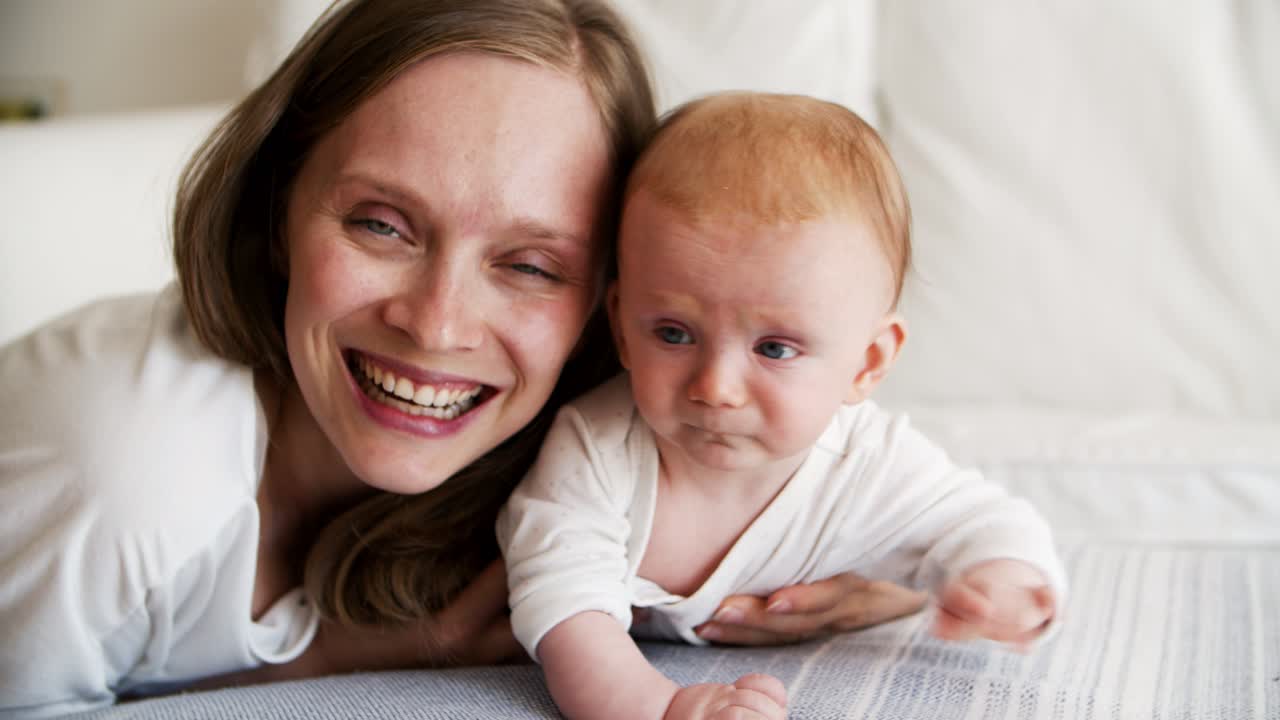 Cheerful mom enjoying and kissing cute baby