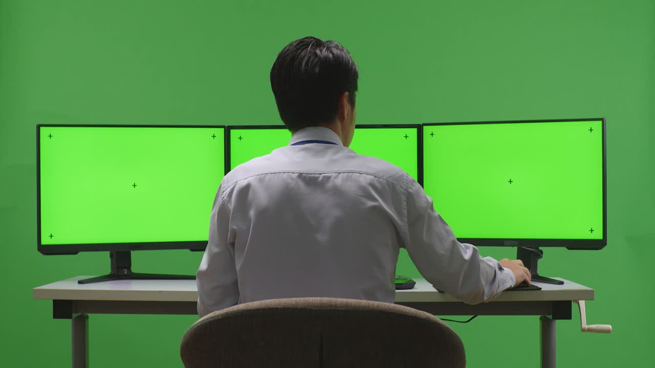 녹색 화면에서 여러 모니터에서 작업하는 사람
