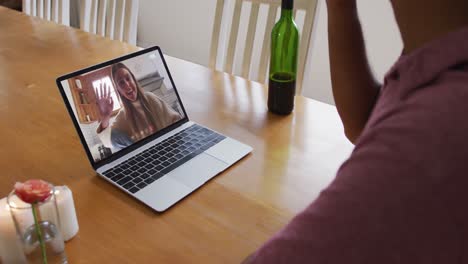 Mid-section-of-african-american-man-drinking-wine-while-having-a-video-call-on-laptop-at-home