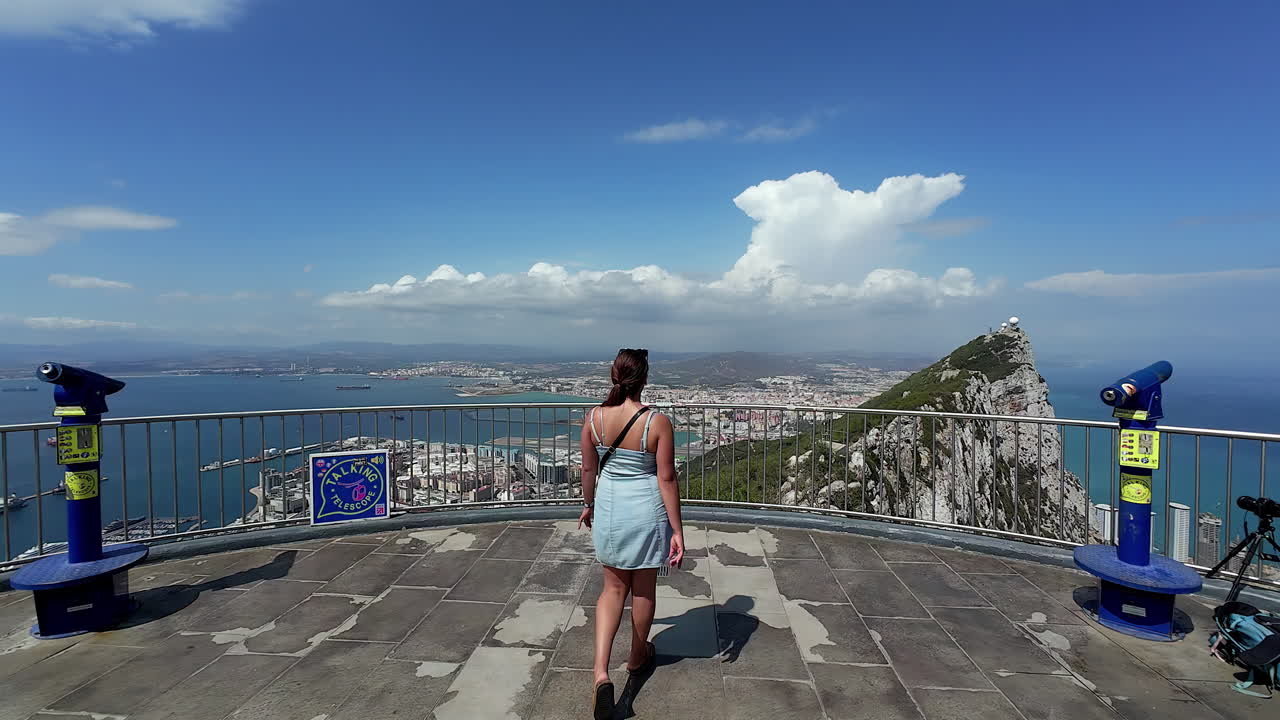 dama acercándose a los rieles para ver la vista panorámica capturada desde la estación superior del teleférico en gibraltar, revelando el paisaje impresionante