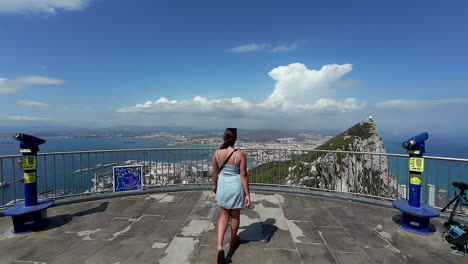 lady approaching rails to see panoramic view captured from the cable car top station in gibraltar, revealing the breathtaking landscape