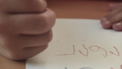 a child writes numbers with a red crayon as the camera tracks left