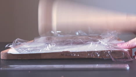 hitting dough with a roller to shape it for baking