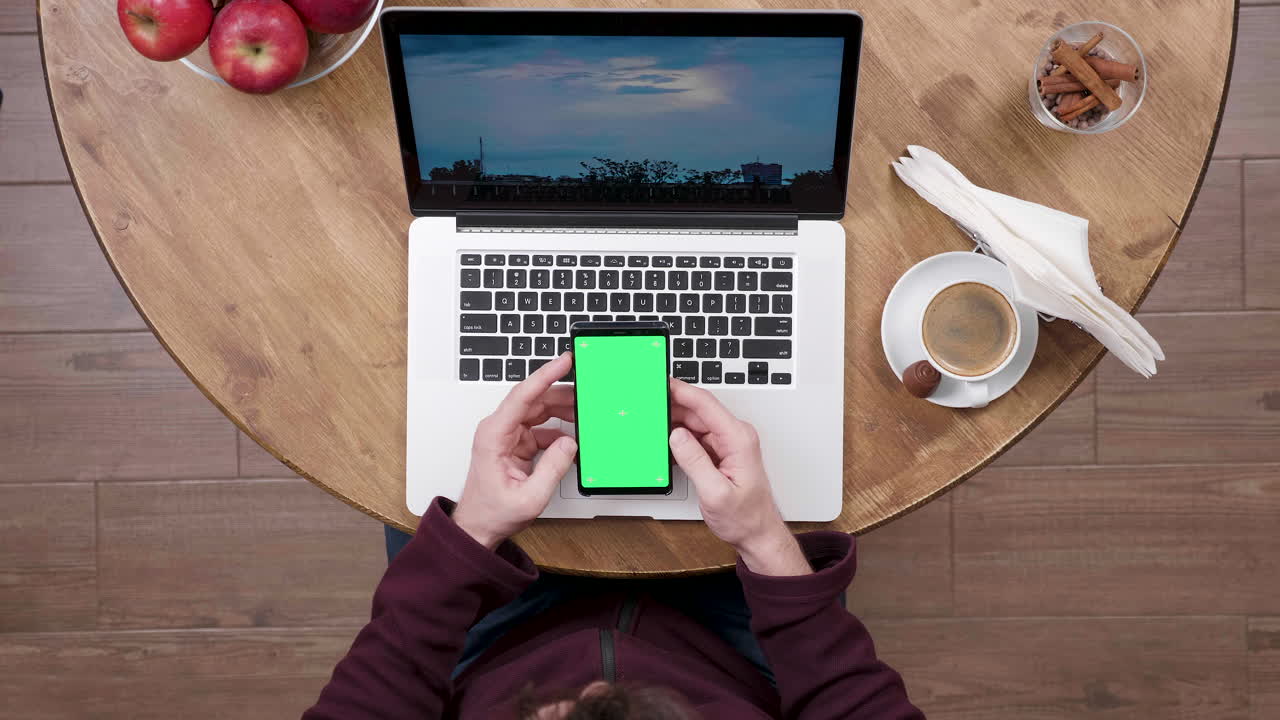 Vista dall'alto di una persona che lavora a un tavolo con un laptop e uno smartphone