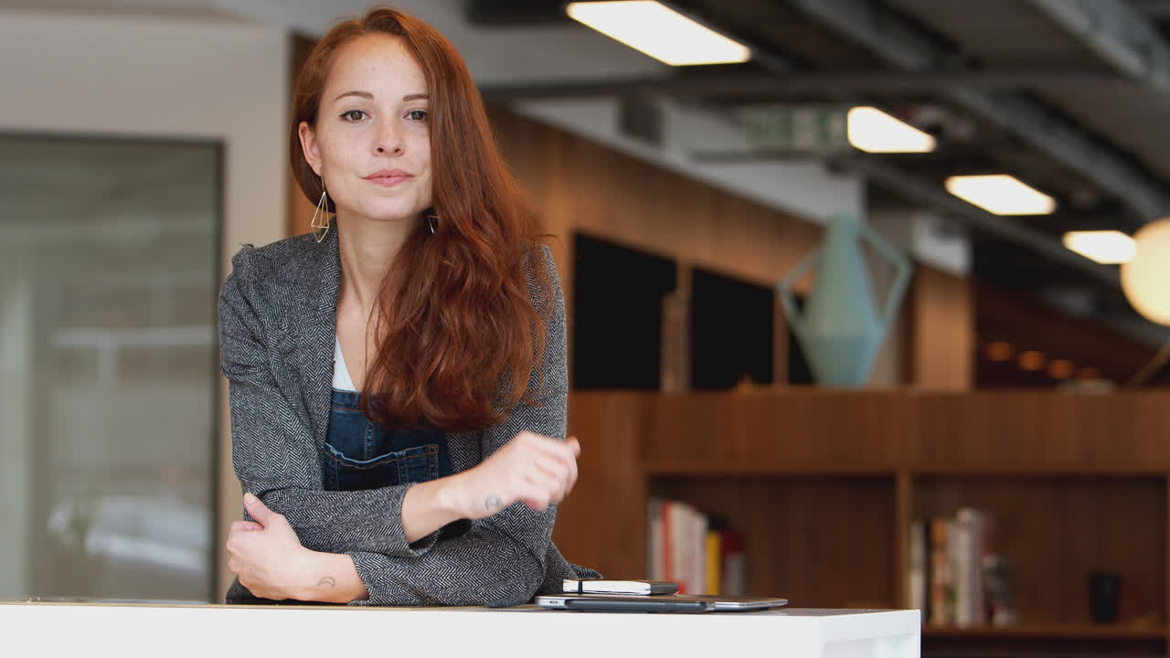 портрет необычно одетой молодой бизнесменки, стоящей на современном рабочем месте с открытым планом