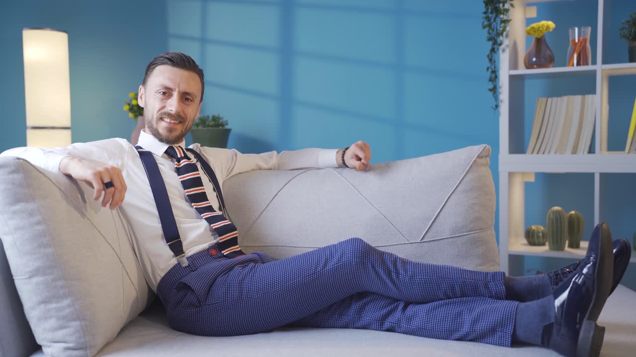 divertido y simpático joven elegante y fresco acostado en el sofá y sonriendo a la cámara.