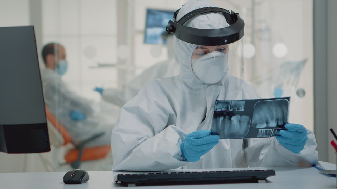 Dentistry specialist holding x ray while using computer