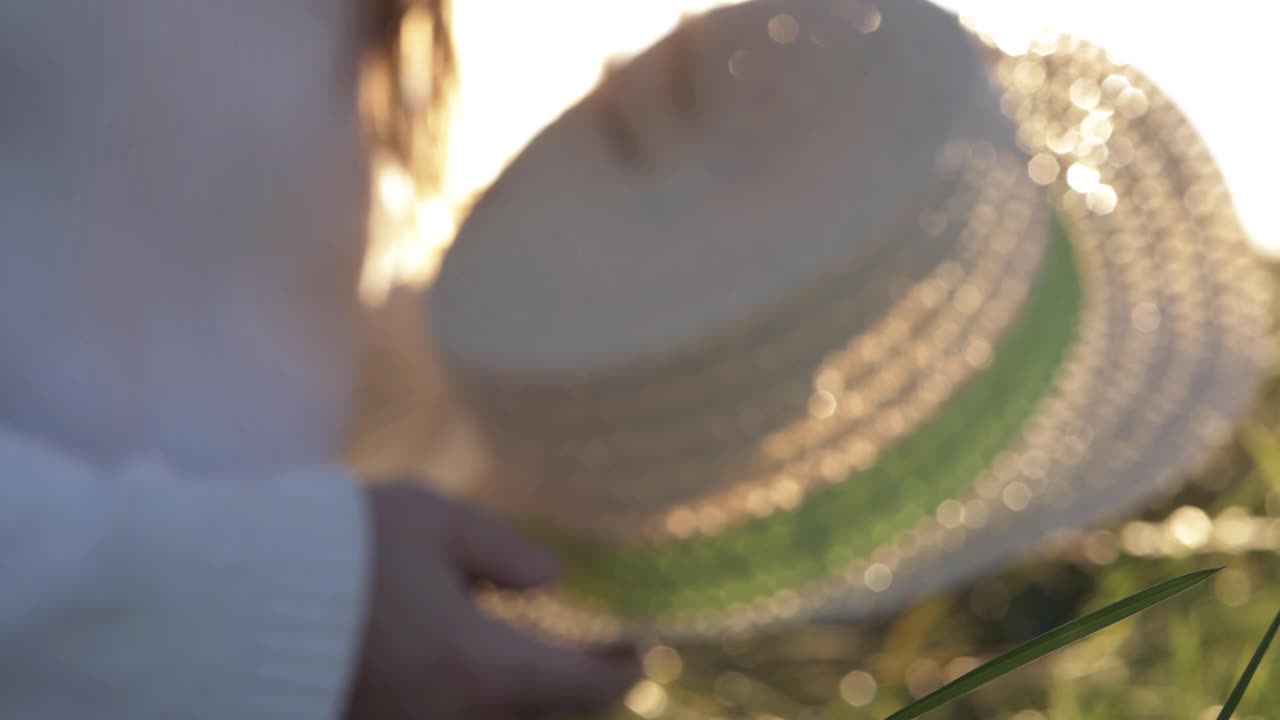 Defocused shot of woman holding straw hat in summer sunshine background abstract medium shot