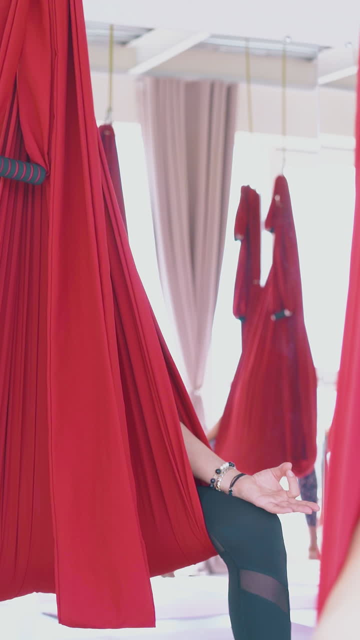 tired after advanced anti-gravity yoga workout women relax in red hammocks holding fingers in mudra position closeup