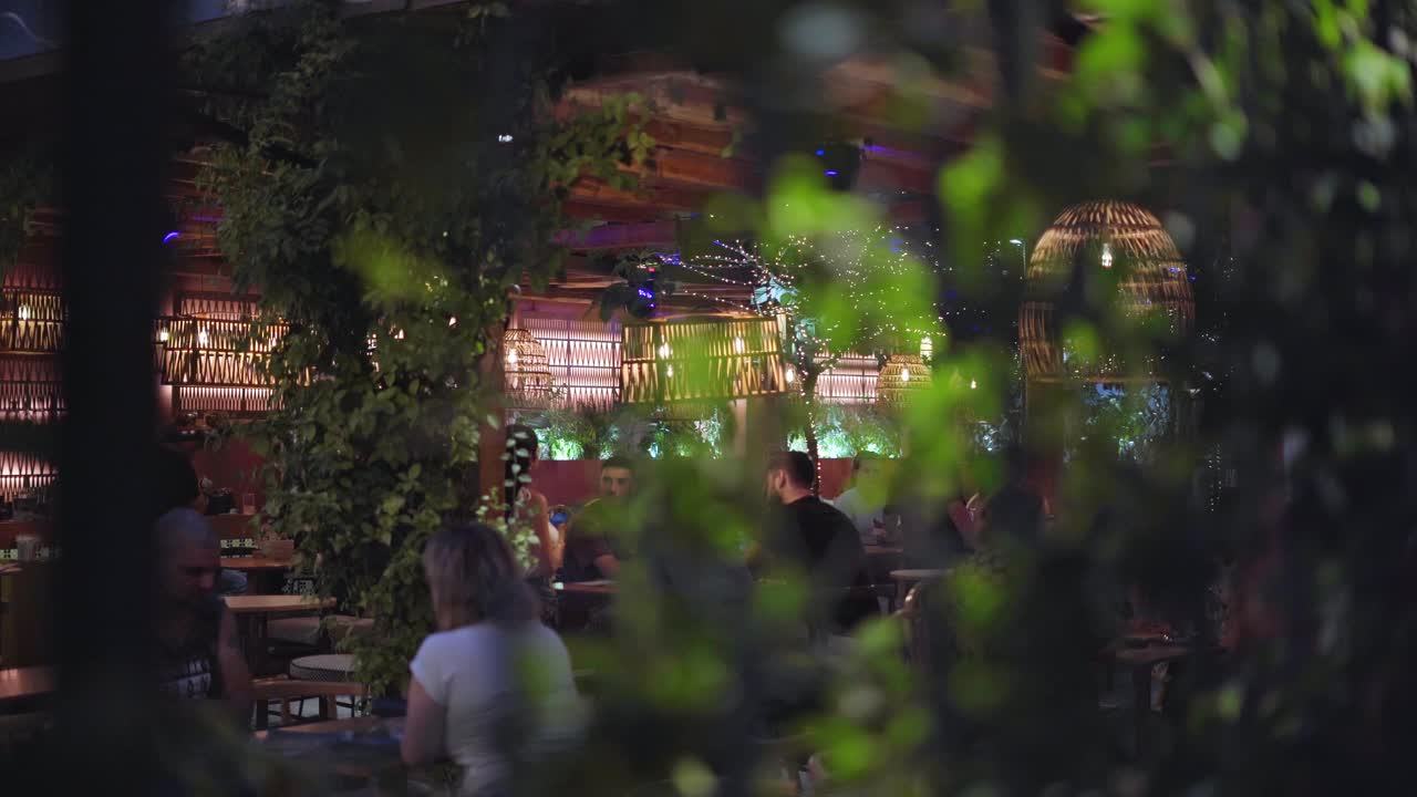 POV of bustling outdoor cafe scene at night, Handheld gimbal shot