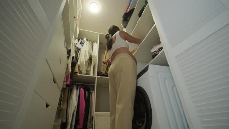 a pregnant woman standing in a modern walk-in closet, thoughtfully selecting an outfit. the scene features stylish clothing and a serene, cozy atmosphere