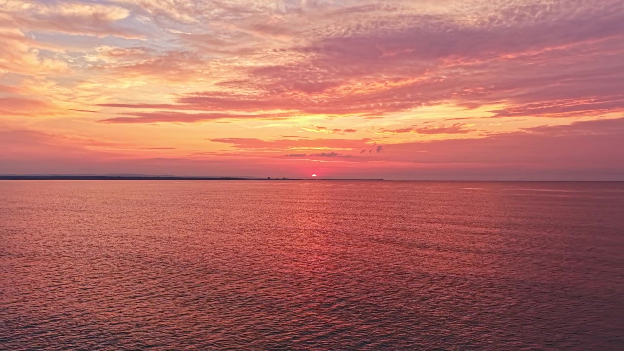 Solnedgang over vandet skaber lyse farver på himlen nær horisonten i aftentimerne.