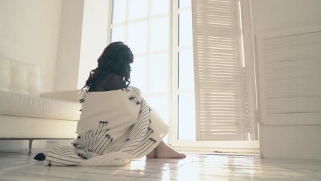 young woman covers herself with plaid on floor backside view