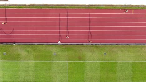 people during early morning jogging on a racetrack with long starched silhouettes, aerial view