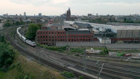 Aerial-View-of-an-double-decker-Inter-City-2-train-entering-the-rail-yard-in-Cologne,-Germany