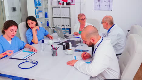 Medical-practioner-checking-list-with-patients-on-clipboard