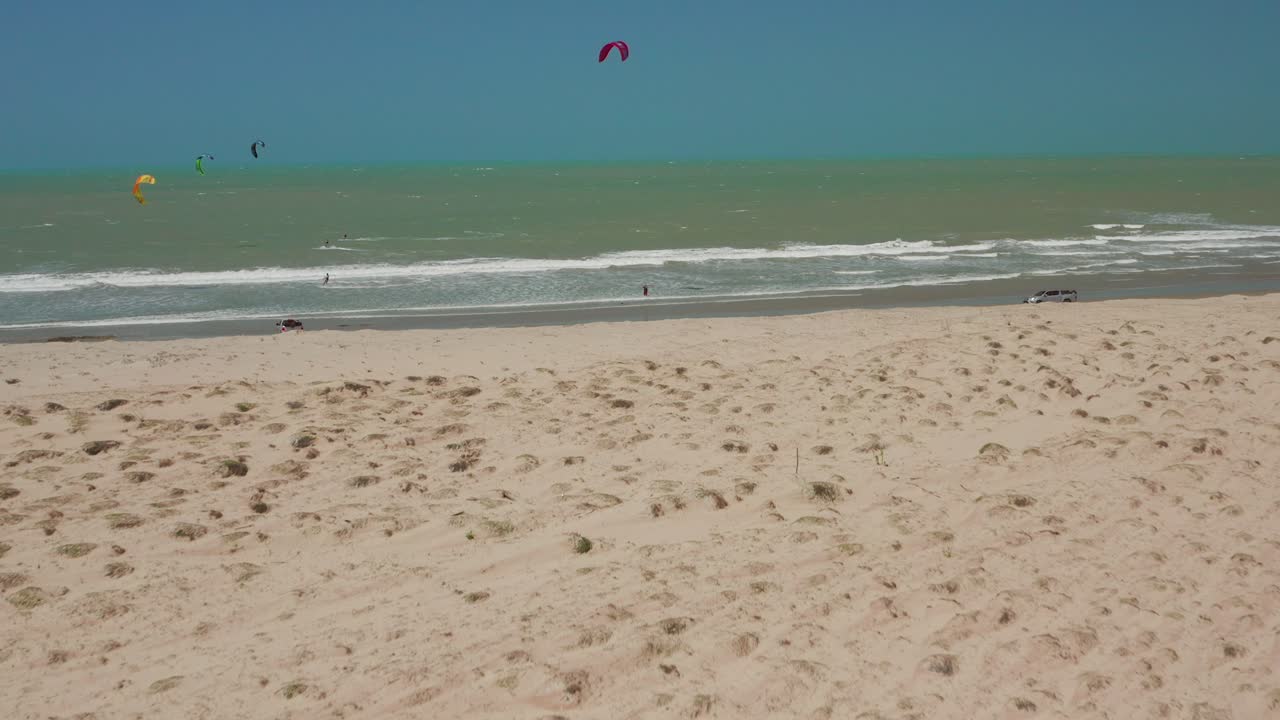 Aerial view of a sandy beach with kite surfers