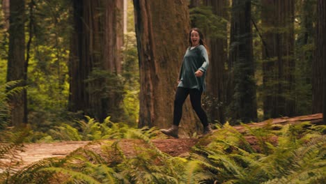a cute girl skips through a redwood forest