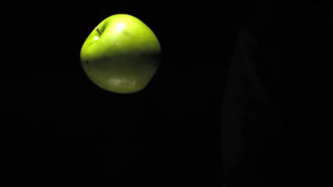 floating green apple illuminated by soft light against dark background