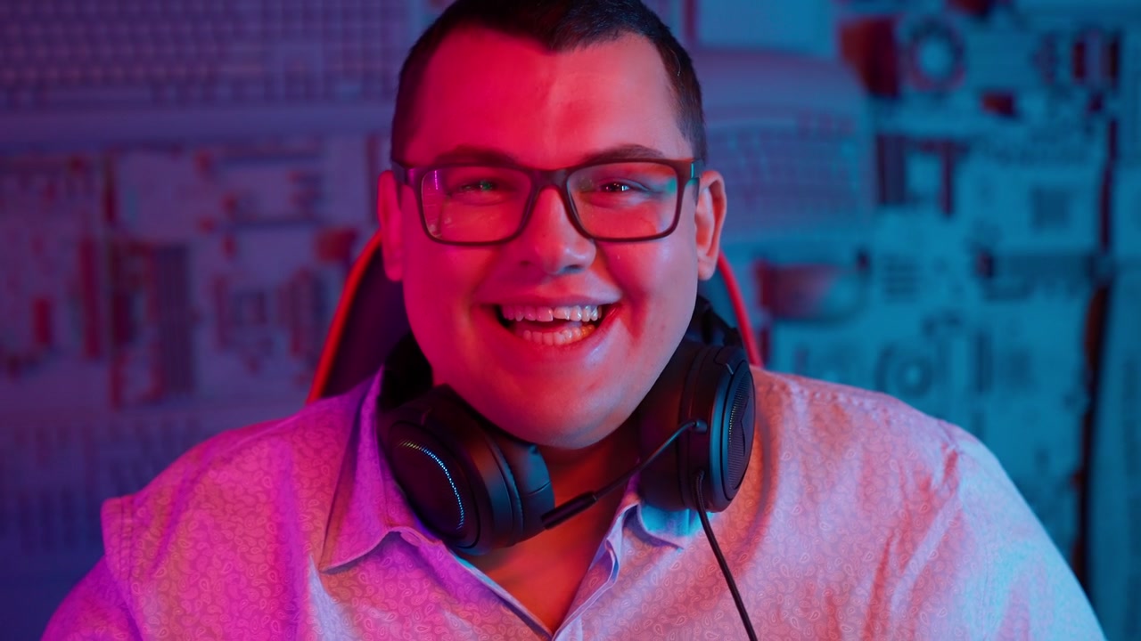Giovane uomo felice con le cuffie che sorride e ride in una stanza illuminata al neon