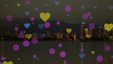 Animation-of-dots-and-hearts-floating-over-blurred-night-cityscape