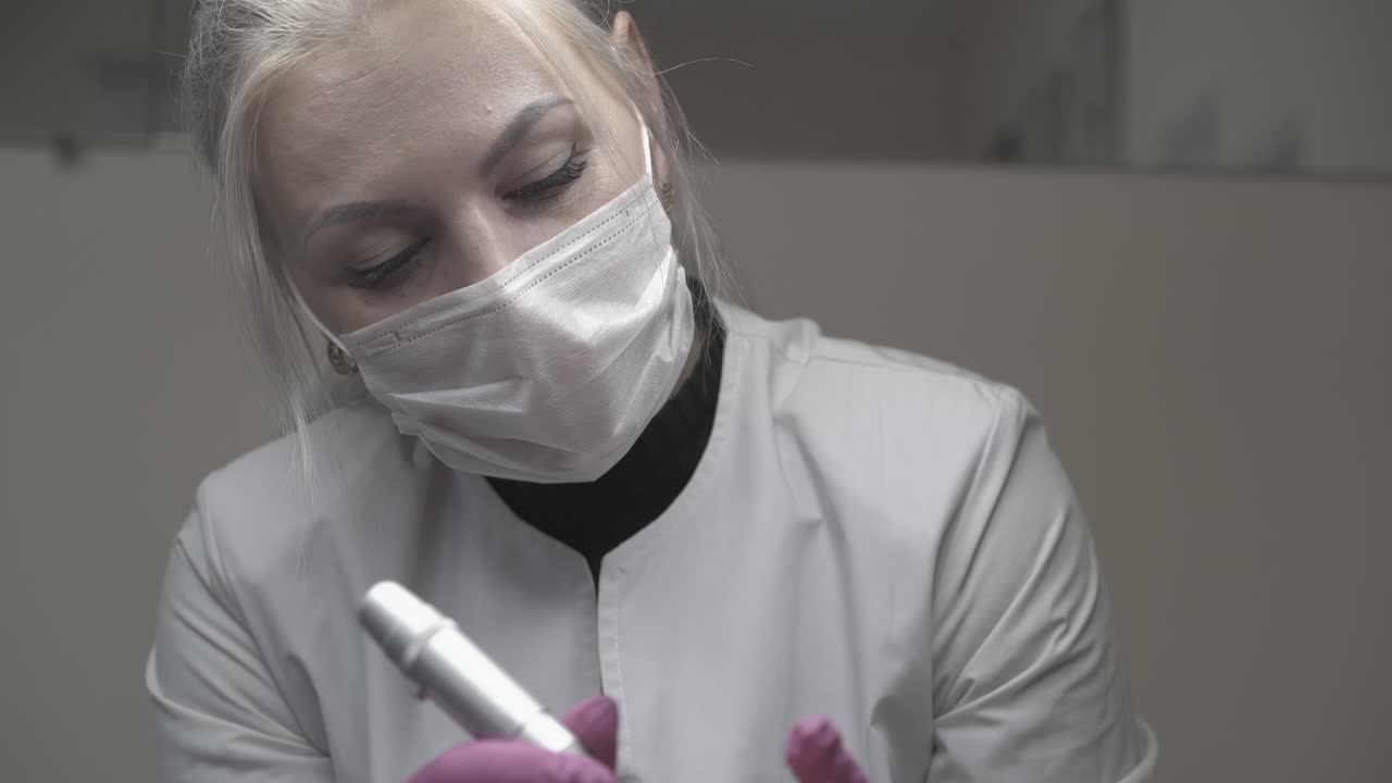 cosmetólogo concentrado aplica maquillaje con una pistola de tatuaje