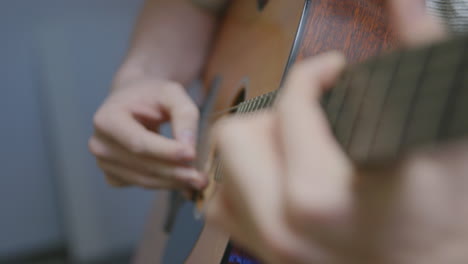 imágenes de primer plano en cámara lenta de los dedos de un hombre tocando y rasgueando una guitarra acústica con un estante enfocado en el cuello de la guitarra