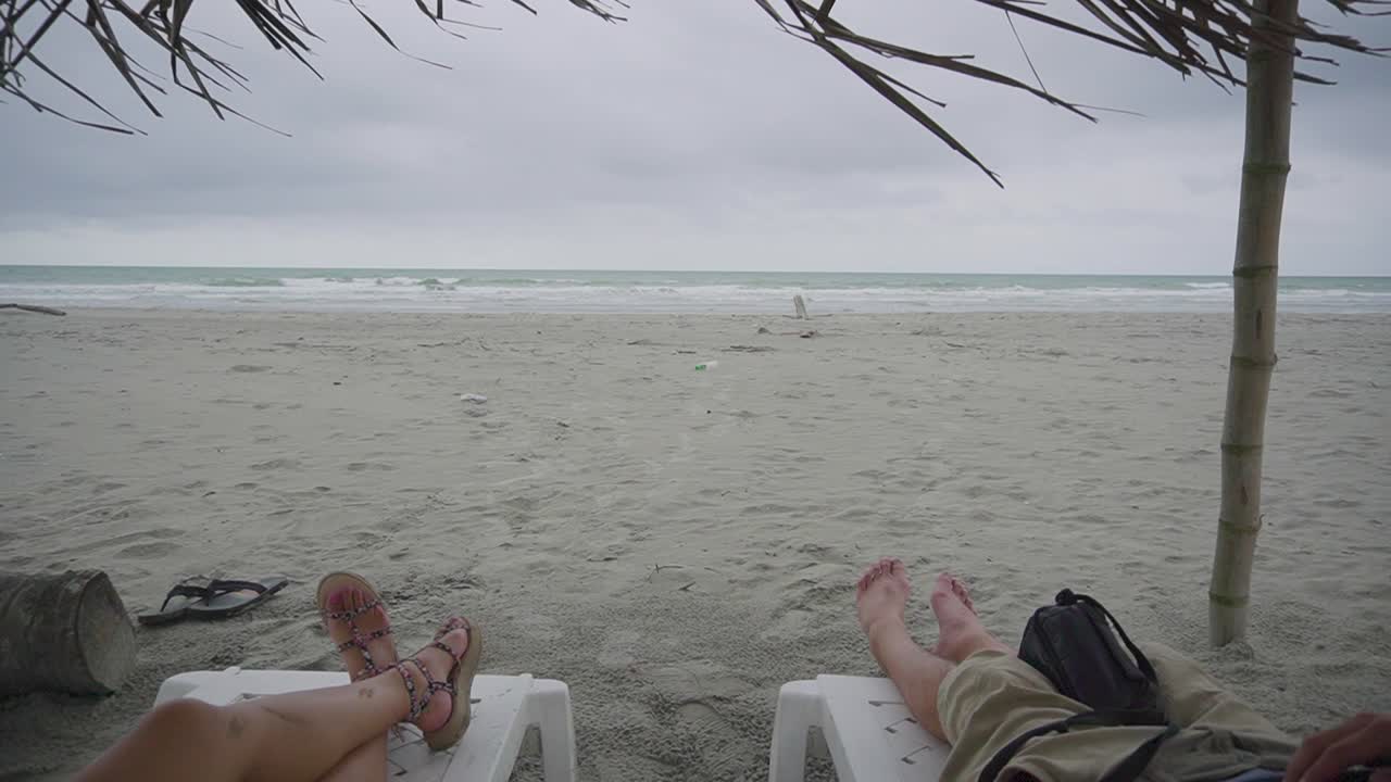 пара загорает в ветреный и штормовой день на песчаном пляже эквадора