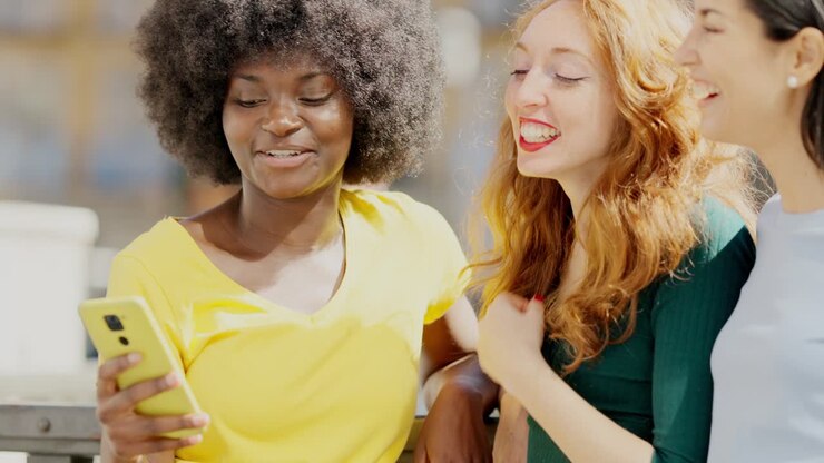 Diverse group of women friends laughing and looking at a smartphone