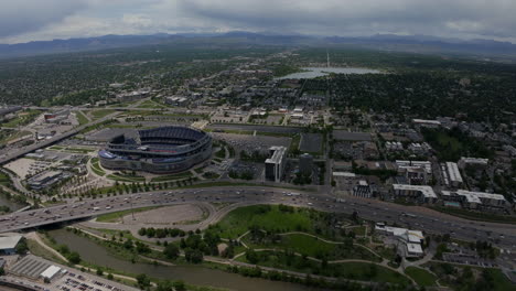 downtown denver aerial drone cinematic mile high stadium denver broncos football south platte river elitch gardens cityscape with foothills rocky mountain colorado cars traffic summer circling