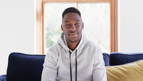 Happy-african-american-man-sitting-on-sofa-and-having-video-call-in-sunny-living-room,copy-space