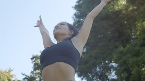 ángulo bajo de una mujer joven y guapa haciendo pose de sol en un parque soleado y hermoso