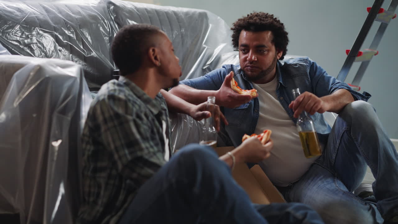 African-American guys eat talk and relax sitting on floor