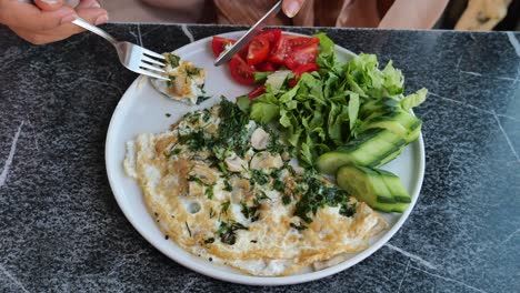 person eating a healthy mushroom omelette breakfast with a side salad