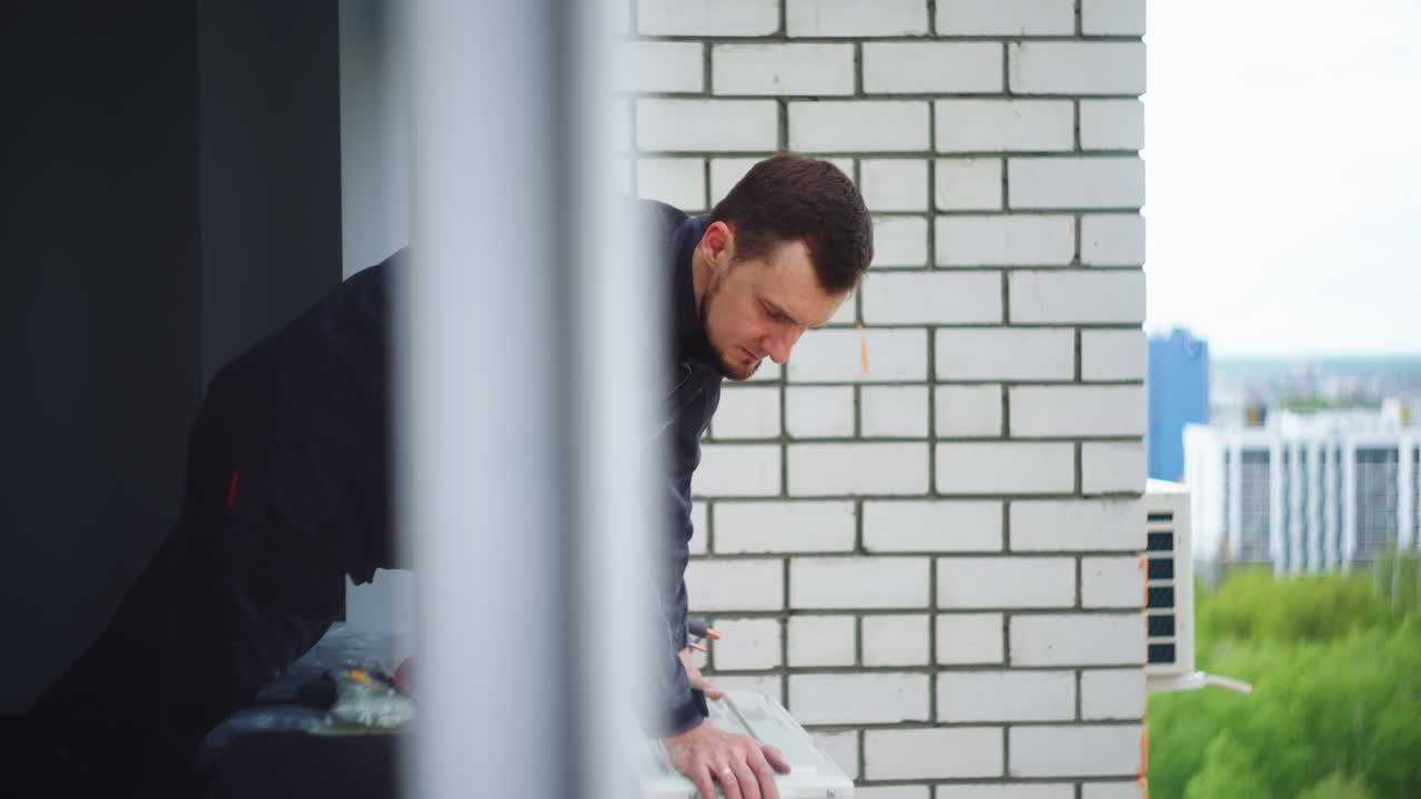 선장은 설치된 에어컨을 점검합니다. 높은 층에 외부 에어컨 유 ⁇ 의 고정 및 설치. 에어 냉각 시스템의 위험한 설치.