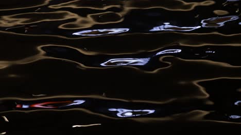 footage of light reflection on the water surface, water waves moving in the dark