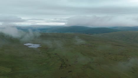 paisaje nebuloso con colinas verdes y manchas de niebla bajo un cielo nublado