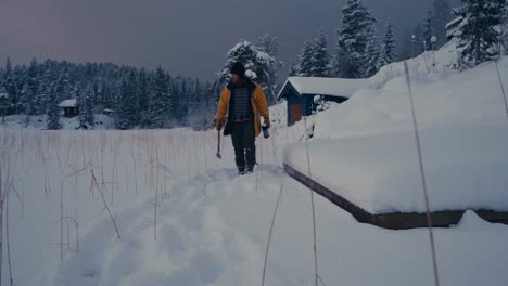 man with axe and vacuum flask walking on snow in winter