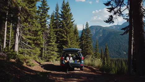 man working remotely from suv trunk in a mountain forest